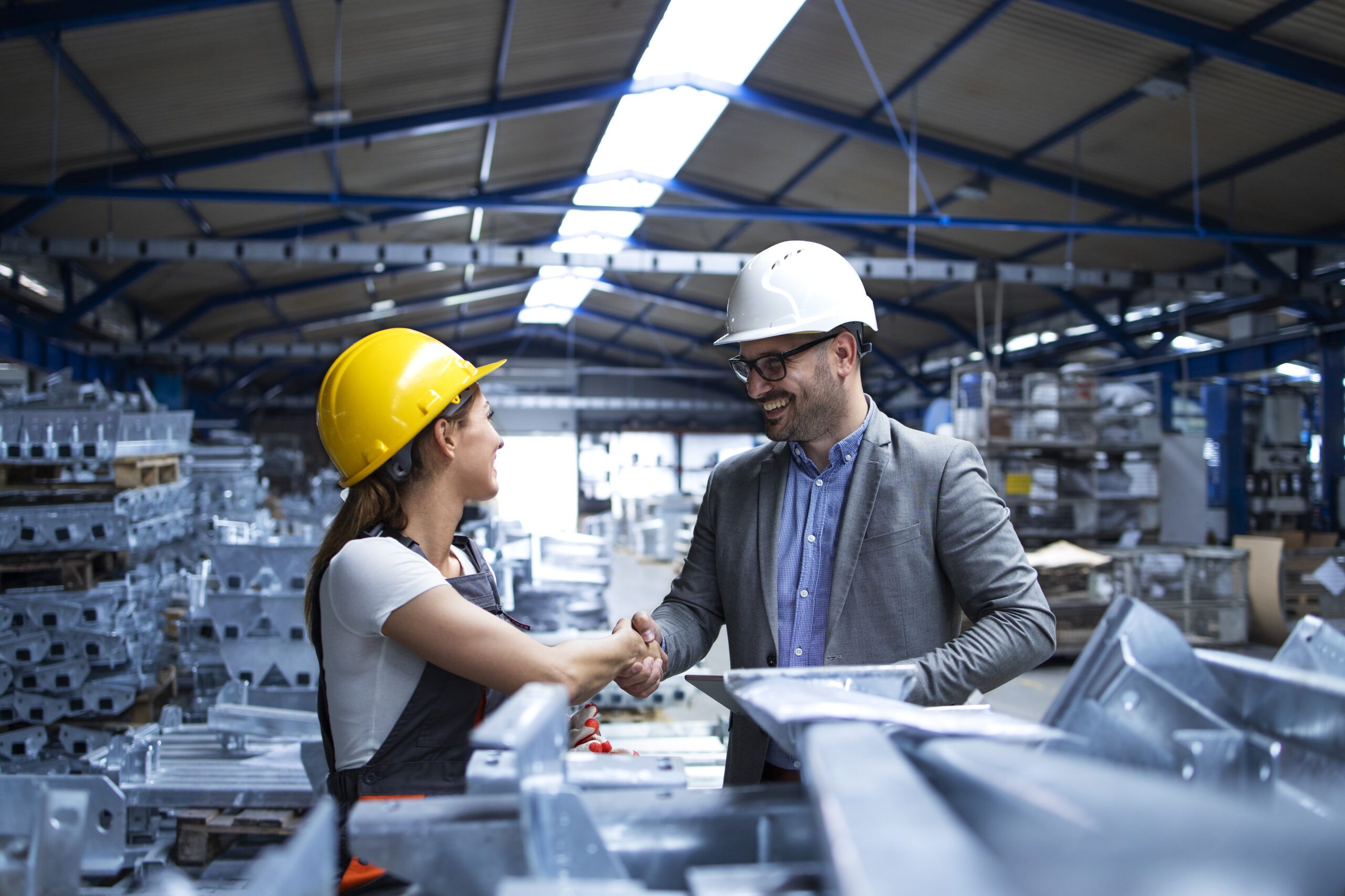 Factory manager visiting production line and congratulating worker on promotion for hard work and good results.